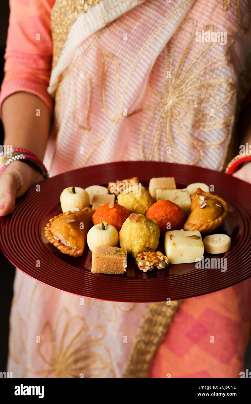 Indische Frau nimmt Diwali Süßigkeiten Gujiya peda barfi Indische süße Dessert mithai Festival Gericht Dussehra Holi ganesh chaturthi RAM navami Durga pooja Stockfoto