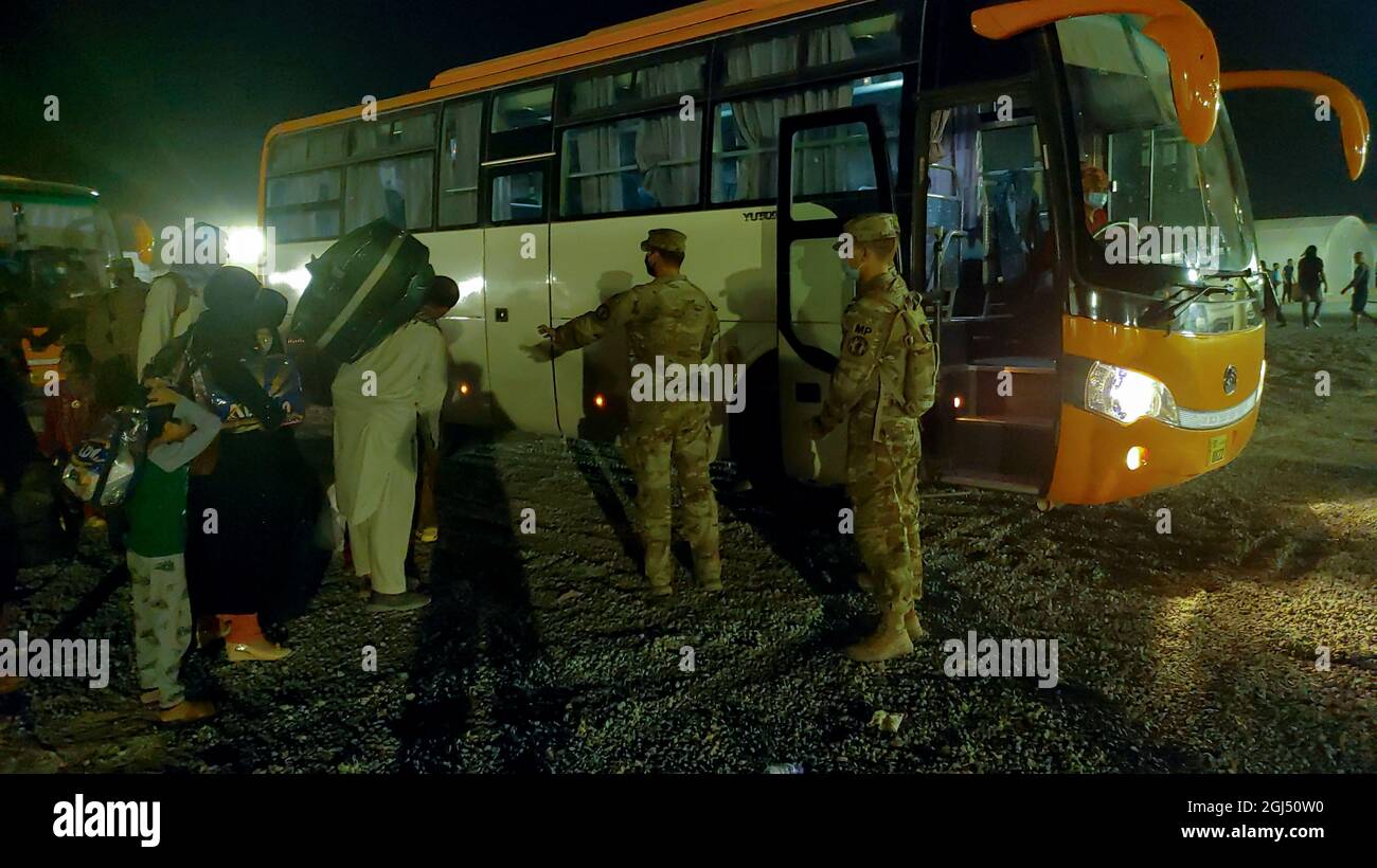 Soldaten der 127. Militärpolizei, des 759. MP-Bataillons und der 89. MP-Brigade helfen afghanischen Evakuierten, an Bord eines Busses auf einem US-Militärstützpunkt in Kuwait zu gehen, 30. August 2021. Der Bus brachte sie zu einer abschließenden Sicherheitskontrolle vor ihrem Flug zum nächsten Ziel. (USA Armeefoto von Sgt. Connor Davis) Stockfoto