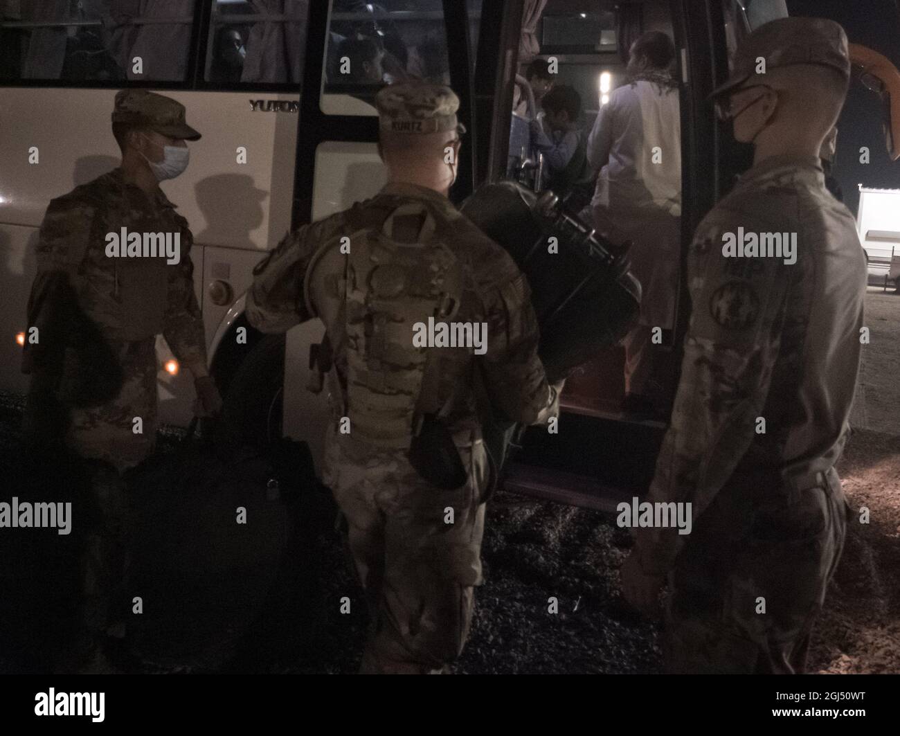 Soldaten der 127. Militärpolizei, des 759. MP-Bataillons und der 89. MP-Brigade helfen afghanischen Evakuierten, an Bord eines Busses auf einem US-Militärstützpunkt in Kuwait zu gehen, 30. August 2021. Der Bus brachte sie zu einer abschließenden Sicherheitskontrolle vor ihrem Flug zum nächsten Ziel. (USA Armeefoto von Sgt. Connor Davis) Stockfoto