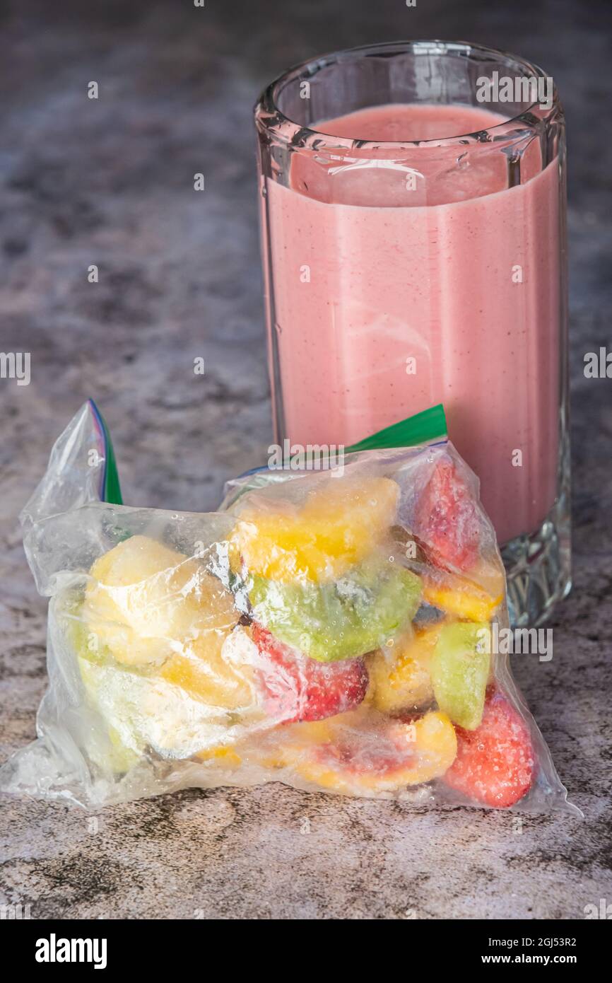 Kaltes Glas Tropical Fruit Smoothie mit Tüte gefrorener Früchte Stockfoto