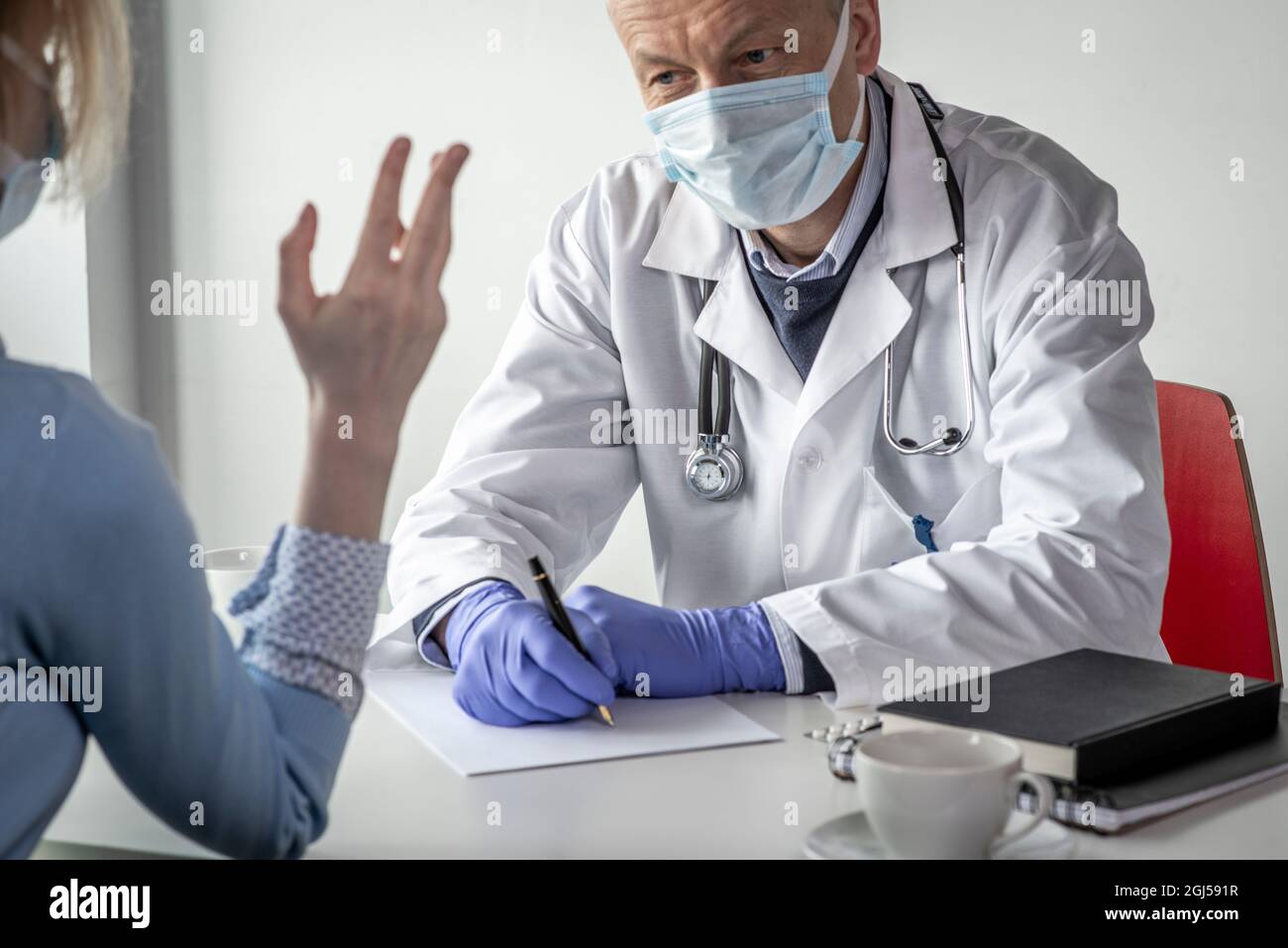 Covid-19, Prävention von Viren, medizinisches Personal und Impfkonzept. Seriös zuversichtlich männlichen Arzt in weißem Mantel und medizinische Maske, trägt eine Brille, Stockfoto