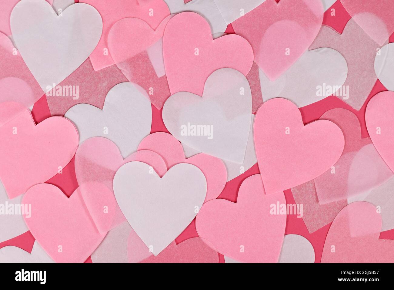 Weißes und pinkes herzförmiges Papierkonfetti auf rosa Hintergrund Stockfoto