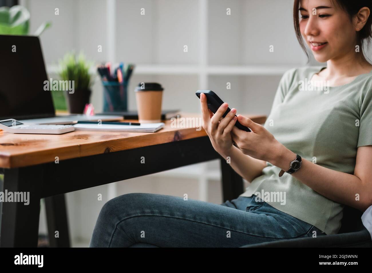 Aufnahme einer asiatischen Frau, die in ihrem Büro mit einem Mobiltelefon in der Buchhaltung telefoniert Stockfoto