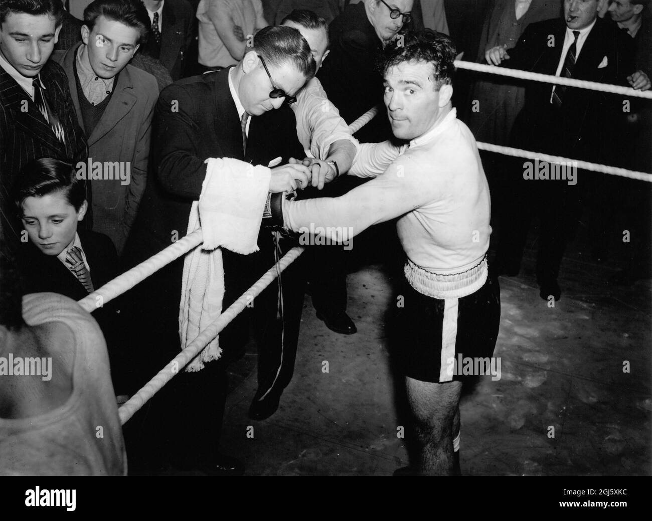 Marcel Cerdan mit seinem Trainer Joe Longman, der vor seinem Training im Cambridge Gym seine Handschuhe bindet. März 1949 Stockfoto