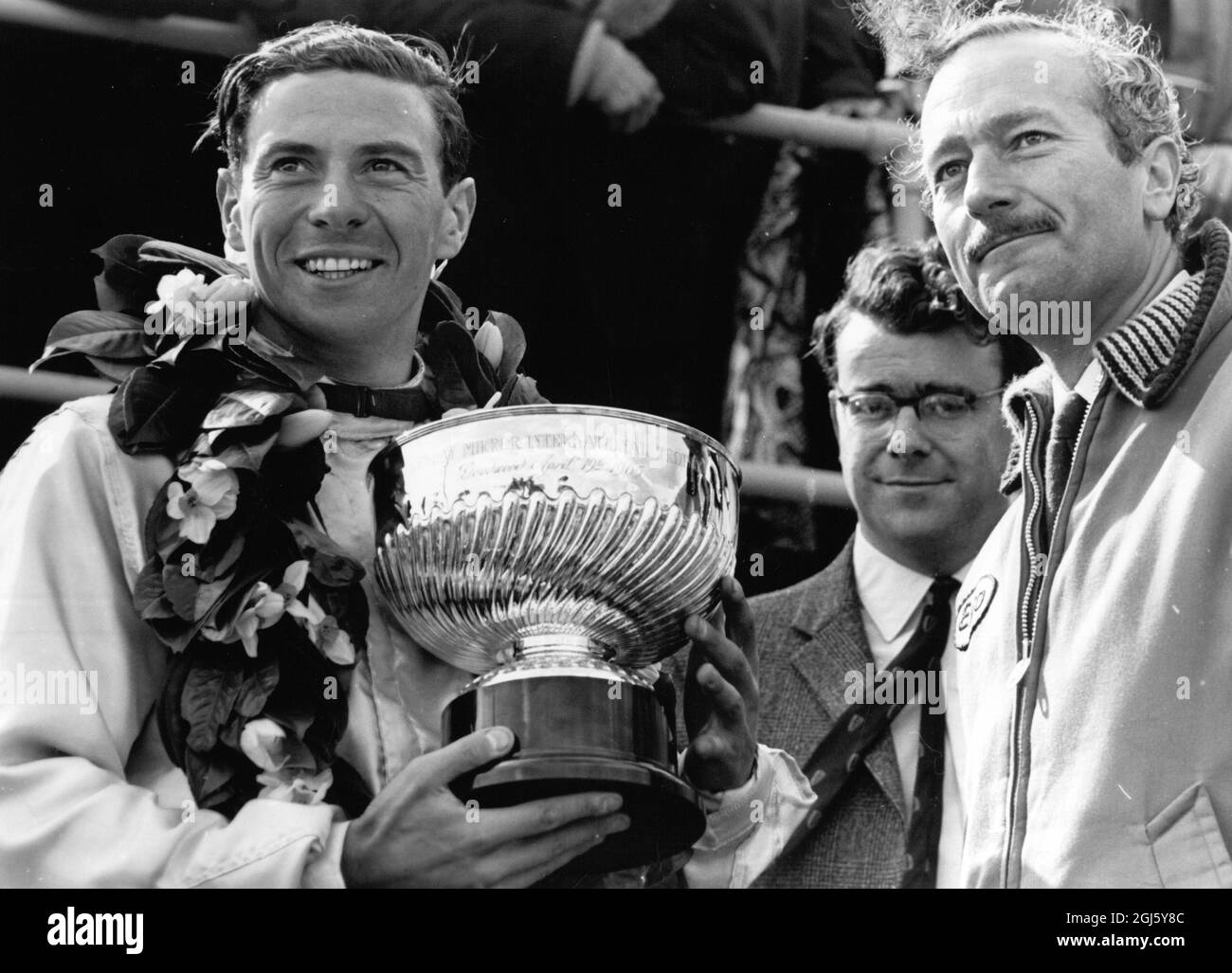 Jim Clark : 1936 - 1968 , britischer Formel-1-Rennfahrer aus Schottland , gezeigt bei Goodwood , Sussex , England , glücklich nach dem Gewinn der International Trophy für den 100 Mile International Grand Prix , mit Colin Chapman auf seiner rechten Seite 19. April 1965 Stockfoto