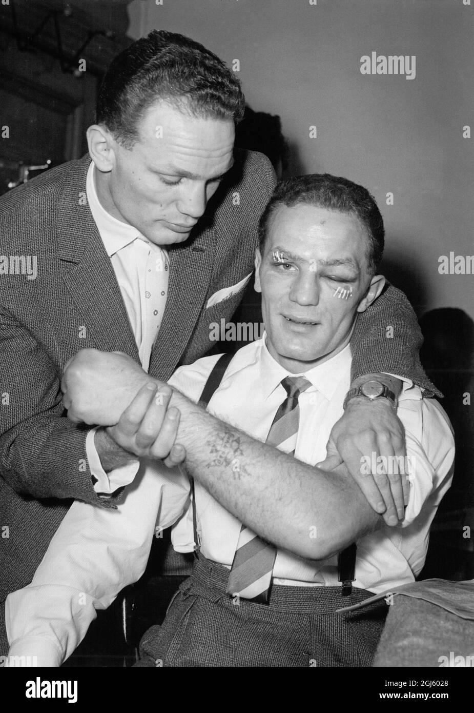 Henry Cooper, mit seinem linken Auge ganz geschlossen und seinem rechten Auge aufgestachelt, zeigt seine linke Hand seinem Zwillingsbruder Jim. 13. Januar 1958 Stockfoto