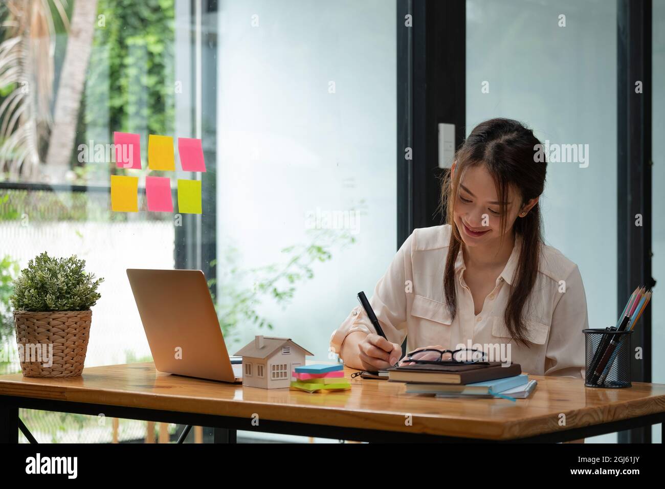 Aufnahme einer asiatischen Immobilienmaklerin, die in ihrem Büro mit einem Laptop arbeitet. Stockfoto