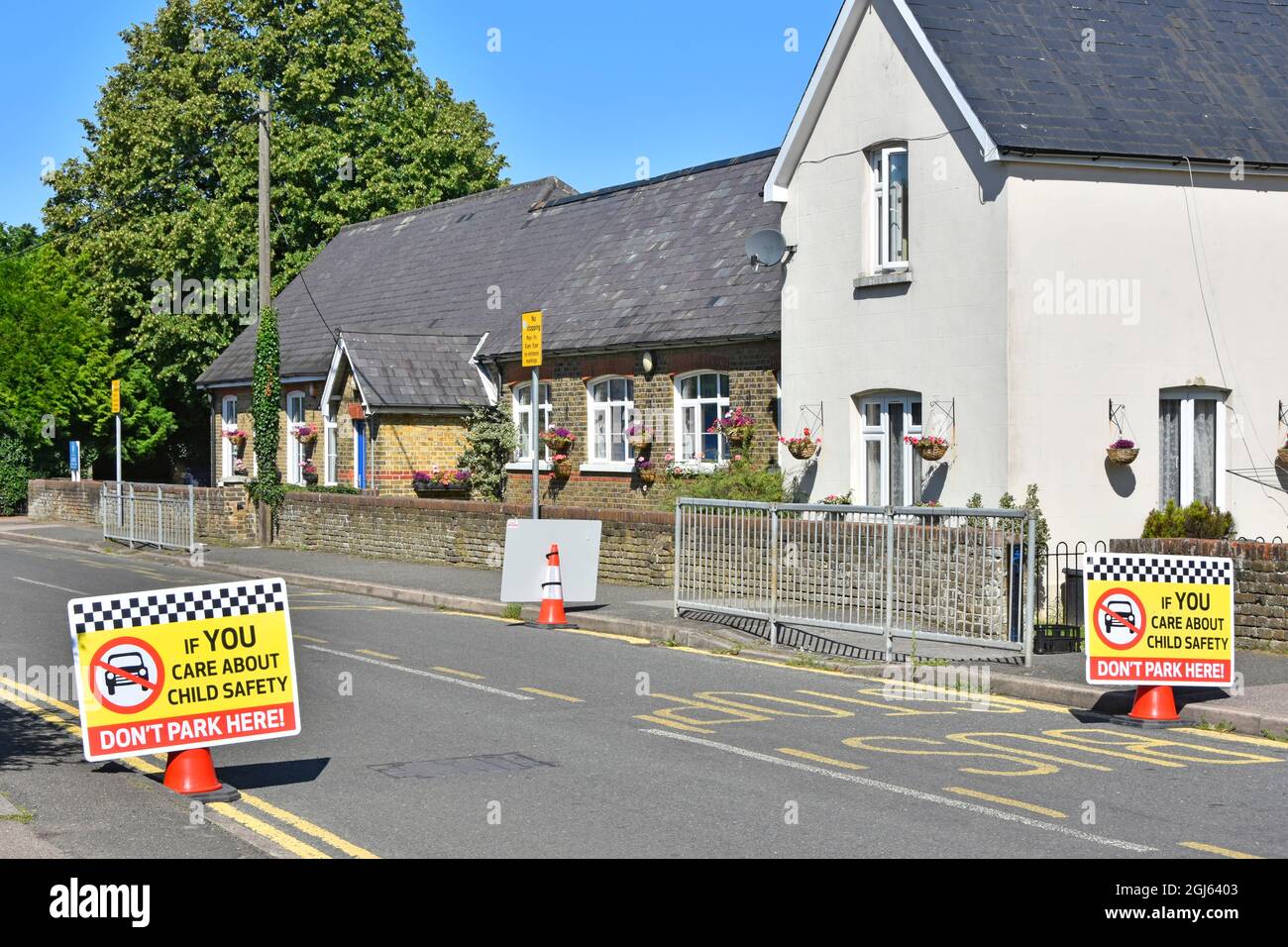 Die Einschränkungen beim Parken auf der Dorfstraße vor dem Tor der Grundschule reichen nicht aus, wenn im Kelvedon Hatch Essex England Großbritannien zusätzliche Kinderfahrsicherheitsschilder verwendet werden Stockfoto