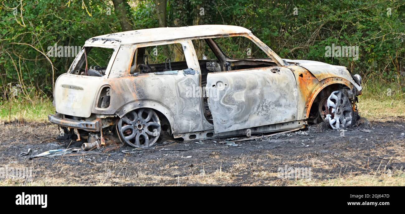 Gestohlenes BMW Mini-Auto in Fackelbrennerei und Ausbrennen in abgelegener ländlicher Landwirtschaft auf verbrannter Erde in Essex England, Großbritannien, zerstört und abgeladen Stockfoto