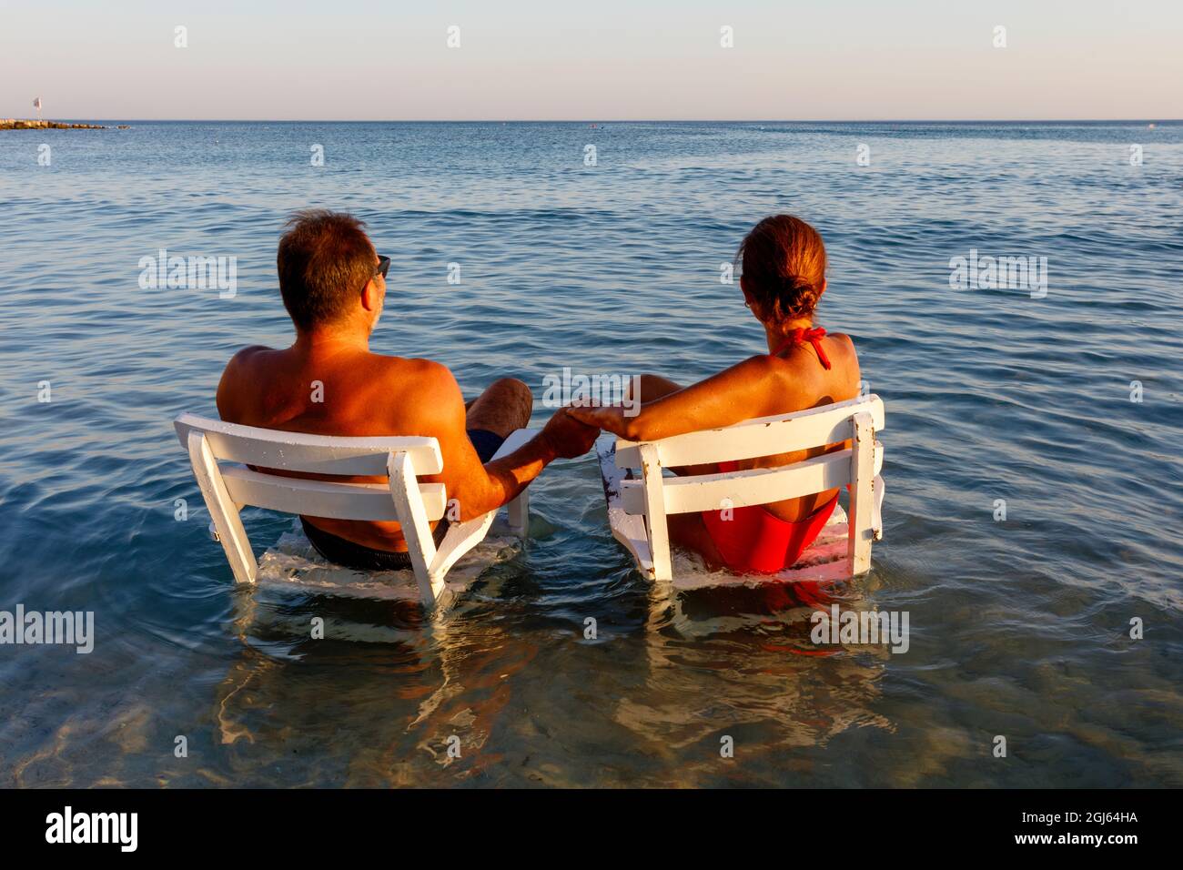 Paar hält die Hände auf Sesseln im Wasser, Strand in Cesme, Izmir, Türkei. Stockfoto