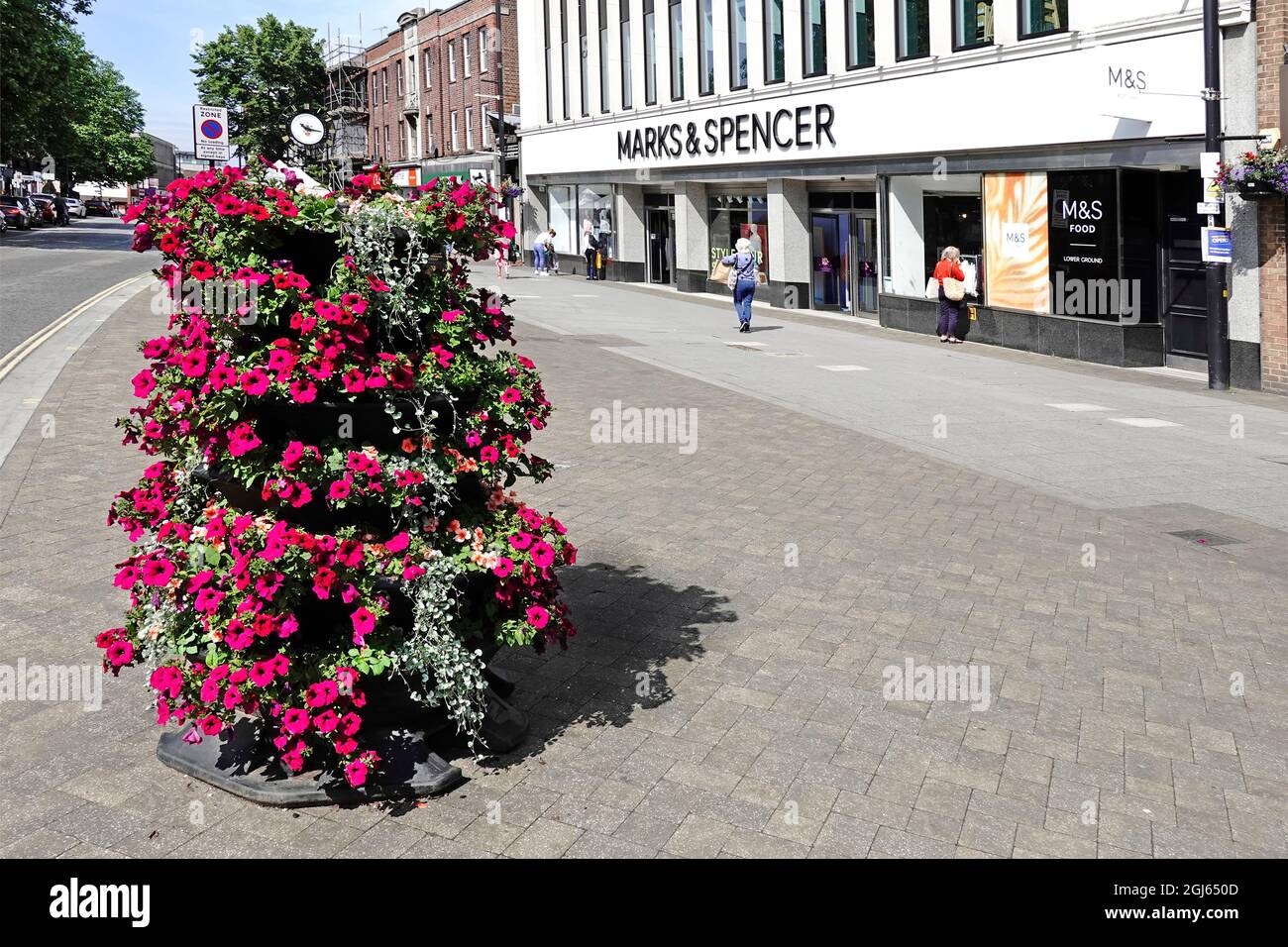 Im Juli, als Großbritannien aus der Pandemie-Blockierung in England herauskommt, werden in der Brentwood High Street Sommerblumen ausgestellt und Marks und Spencer nur wenige Käufer laden Stockfoto
