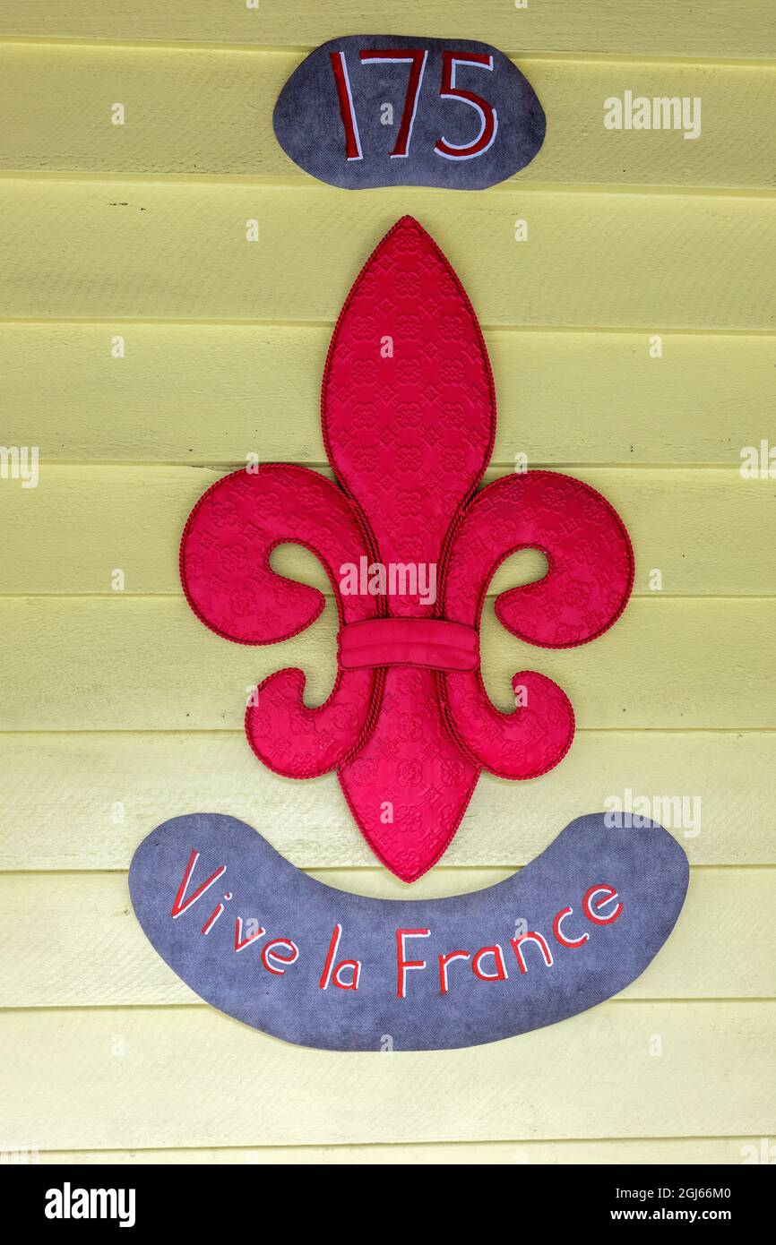 Rotes gestepptes Stofffleur-de-Lis Vive la France Schild vor Einem Gebäude in Akaroa, Neuseeland Stockfoto