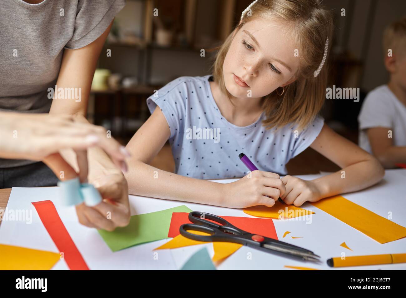 Kleines Mädchen arbeitet in der Werkstatt mit farbigem Papier Stockfoto