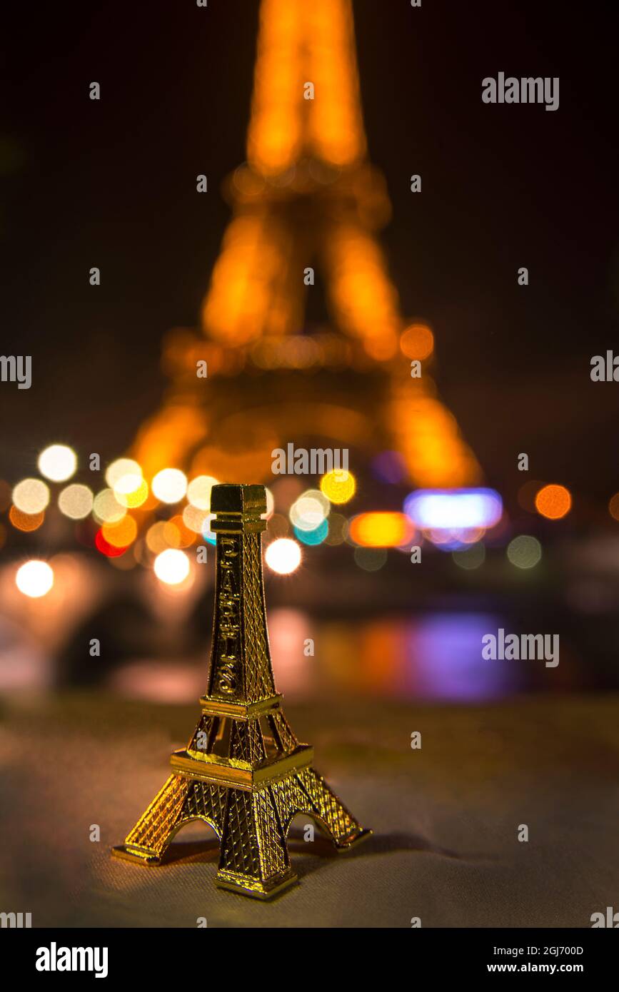 Ein Souvenir-Eiffelturm an der Wand der seine gegenüber der realen Sache Stockfoto