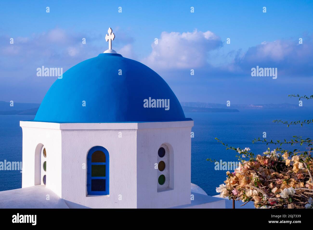 Blau gewölbte griechisch-orthodoxe Kirche mit Bougainvillea-Blumen in Oia, Santorini, Griechenland. Stockfoto