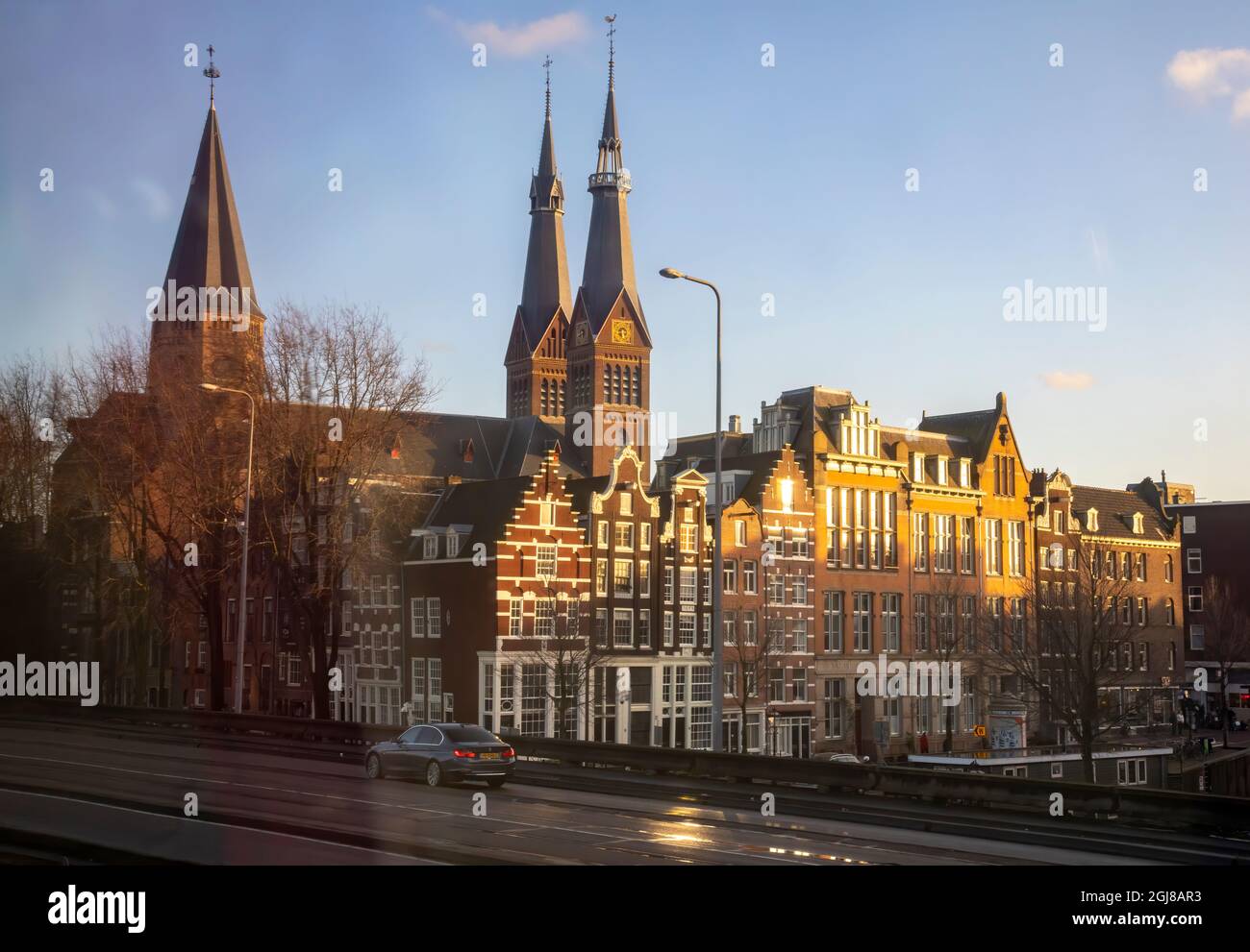 Europa, Niederlande, Amsterdam. Die Kirche von Post Horn steht in der Dämmerung auf Türmen und Reihenhäusern. Stockfoto