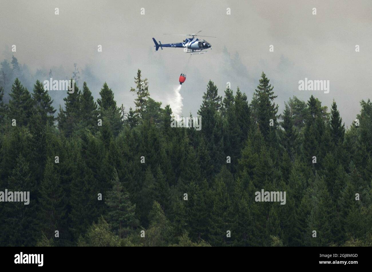 GAMMELBY 20140804 Ein Hubschrauber stürzt seine Wasserlast am 4. August 2014 an der Feuerfront vor dem evakuierten Dorf Gammelby in der Nähe von Sala, Mittelschweden, ab. Das Feuer, das Tausende von Hektar umfasst, ist am fünften Tag und die Feuerwehrleute glauben, dass es Wochen- oder sogar monatelang brennen wird. Es wird als der schlimmste Waldbrand in Schwedens moderner Geschichte eingestuft. Foto: Fredrik Sandberg / TT / Kod 10080 Stockfoto