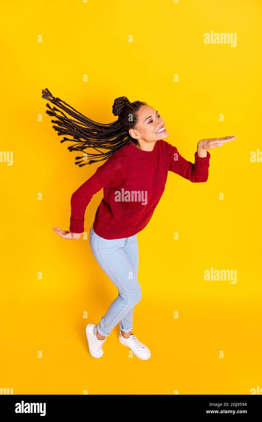 Vertikale voller Länge Foto von süßen lustigen dunklen Haut Dame tragen roten Pullover lächelnd tanzen isoliert gelben Hintergrund Stockfoto