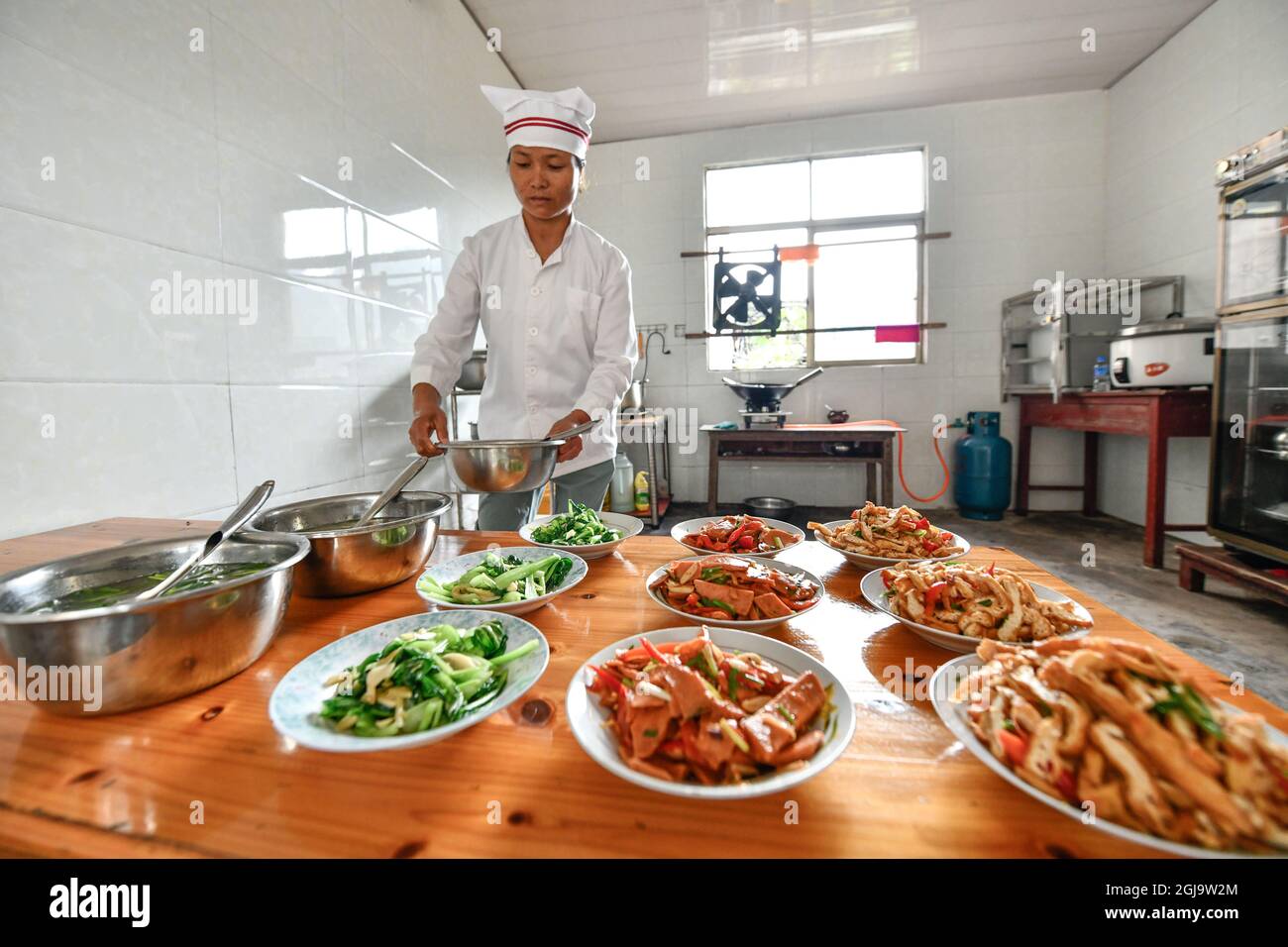 (210909) -- ZHENYUAN, 9. September 2021 (Xinhua) -- Zhu Muqun bereitet am Pingyu-Lehrort des Dorfes Songbai, Gemeinde Baojing des Bezirks Zhenyuan, südwestlich der chinesischen Provinz Guizhou, eine Mahlzeit für Studenten vor, 8. September 2021. Der Pingyu-Lehrort liegt tief in der Bergregion des Bezirks Zhenyuan, der autonomen Präfektur Qiandongnan Miao und Dong, südwestlich der Provinz Guizhou, und wird hauptsächlich von einem Paar unterstützt. Im Jahr 2000 schloss Pan Zhongyong eine normale Schule ab und kam als Lehrer an die Pingyu-Lehrstelle. Später traf er Zhu Muqun, ein Mädchen im Dorf, und heiratete sie. Im Laufe der Jahre, t Stockfoto