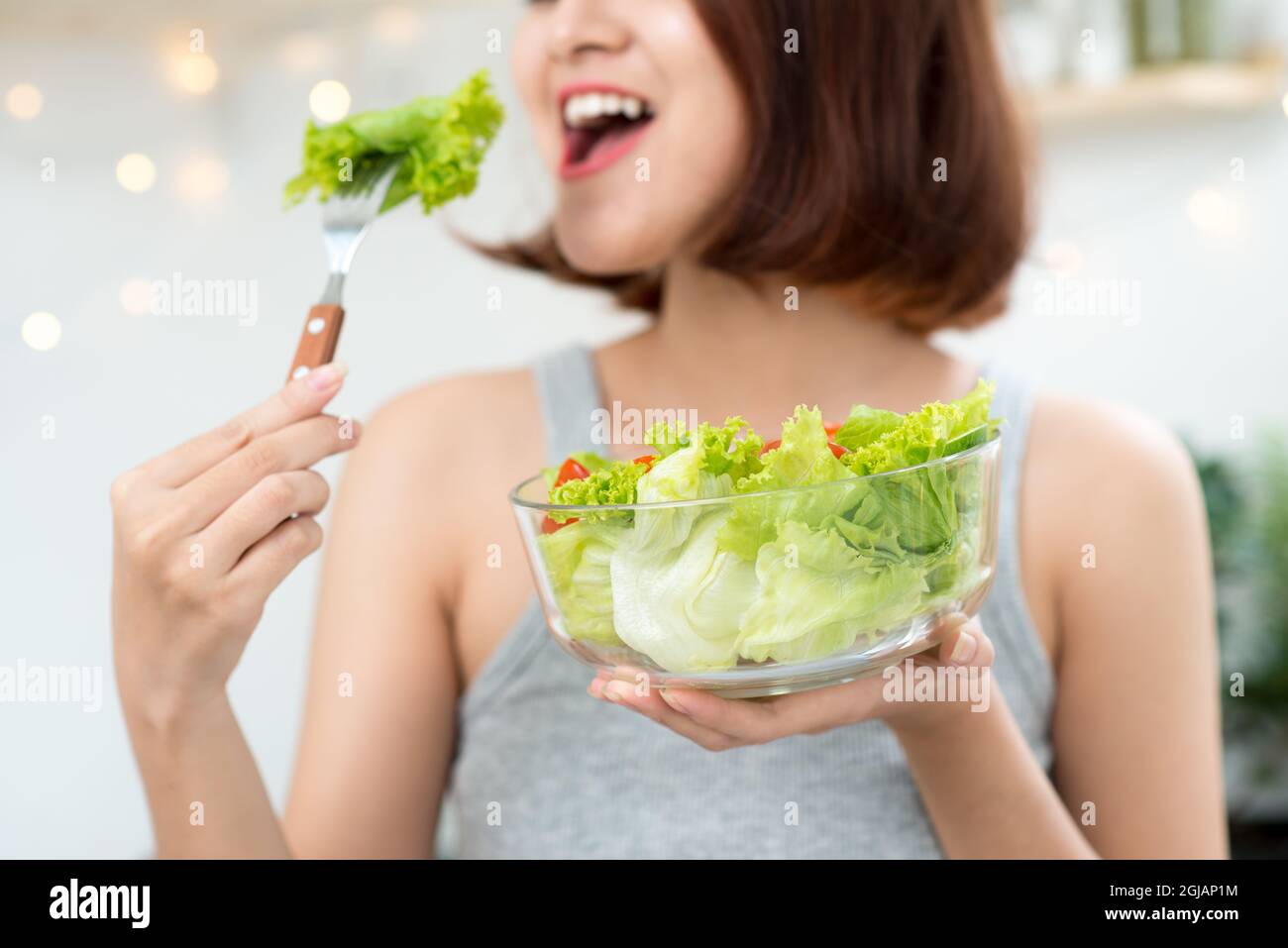 Schöne junge Asiatin Salat essen. lächelnde glückliches Mädchen, gesunde Ernährung. Stockfoto