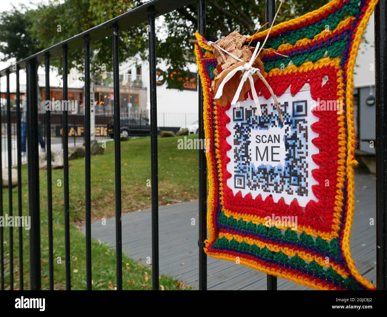 Guerilla-Marketing. QR-Code mit Scan Me Invitation in einer Garnbombendekoration, die auf einem Geländer in einer Innenstadt platziert ist. Plymouth, Großbritannien. Stockfoto