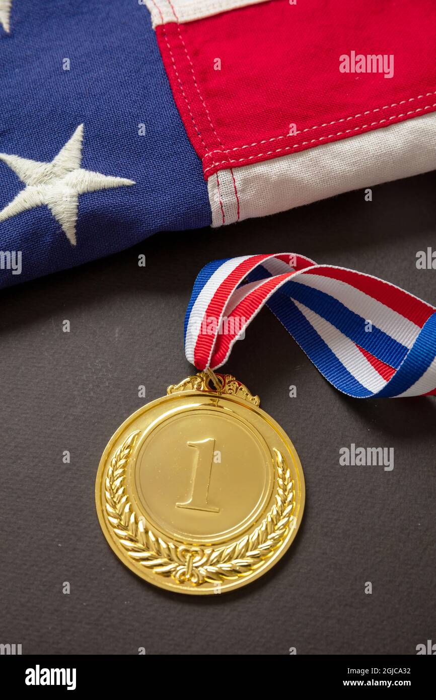 Goldmedaille für die USA. Siegerpreis mit Band und US-Flagge auf schwarzem Hintergrund. Trophäe des amerikanischen Sportlers für den ersten Platz des Champions. Stockfoto