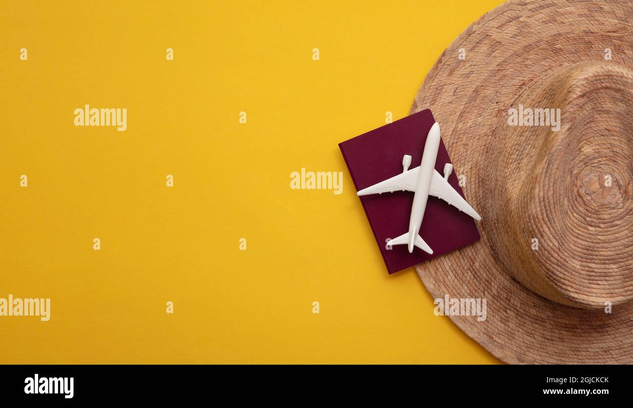 Strohsonnenhut mit Reisepass und Modellflugzeug. Sommerurlaub Hintergrund Stockfoto