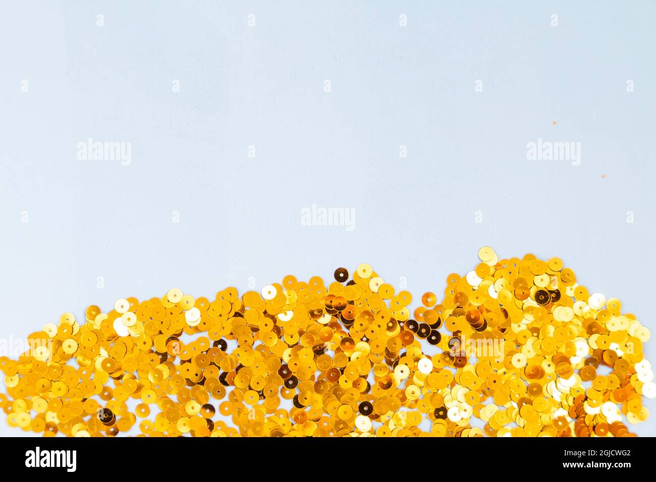 Hellblauer Hintergrund mit goldenem Konfetti, selektiver Fokus Stockfoto