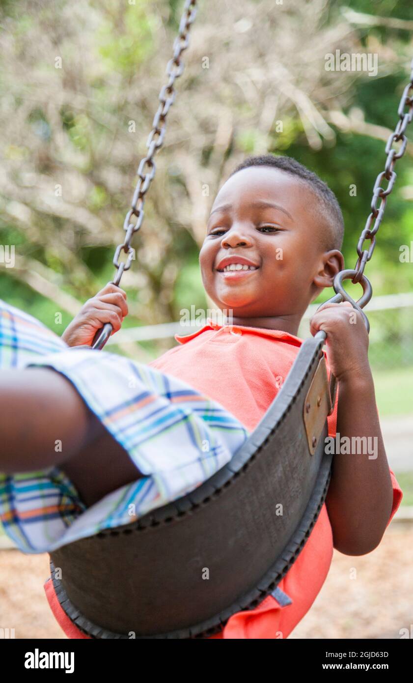 Junger afroamerikanischer Junge im Alter von 4 Jahren spielt auf Schaukel im Park in Florida (MR). Stockfoto