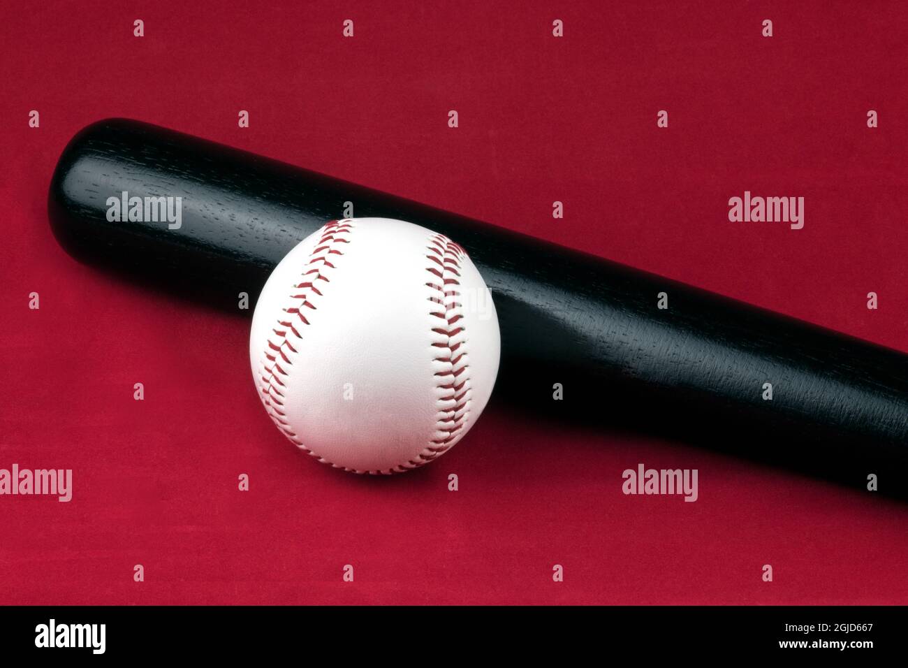 Weißer weicher Ball und schwarzer Baseballschläger auf rotem Hintergrund Stockfoto