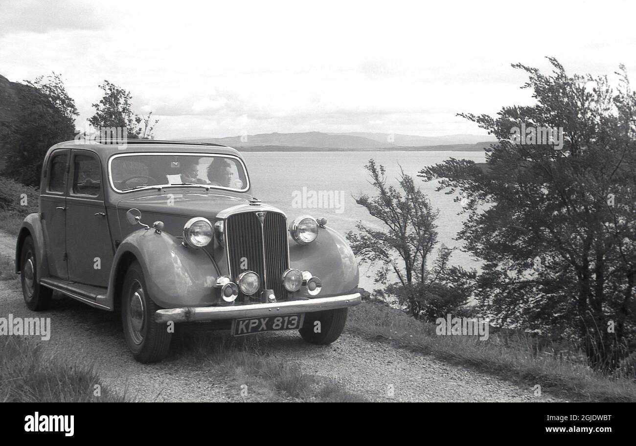 In den 1950er Jahren, historischer Autourlaub im schottischen Hochland, zwei Damen, die in einem in Großbritannien hergestellten Rover-Sportwagen sitzen, einem 75-Light-Sportlimousine Rover 4 P3, geparkt auf einer Schotterpiste neben einem loch, Schottland, Großbritannien. Stockfoto