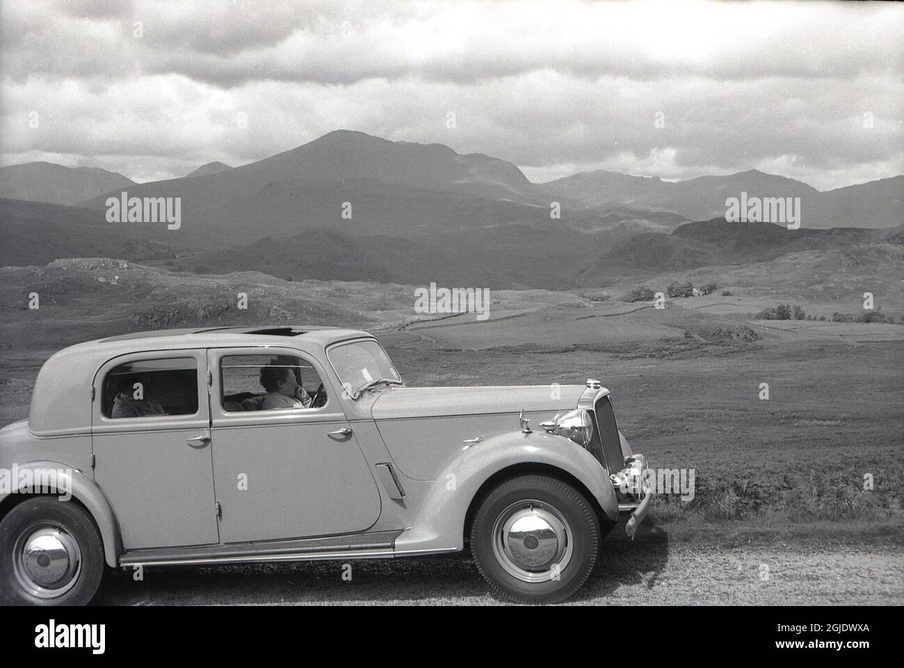 In den 1950er Jahren, historisch, fuhr im schottischen Hochland, zwei Damen sitzen in einem britischen Rover-Motorwagen, einem Rover 75 P3 4-Light-Sportlimousine, geparkt am Rande einer Landstraße, Schottland, Großbritannien. Stockfoto