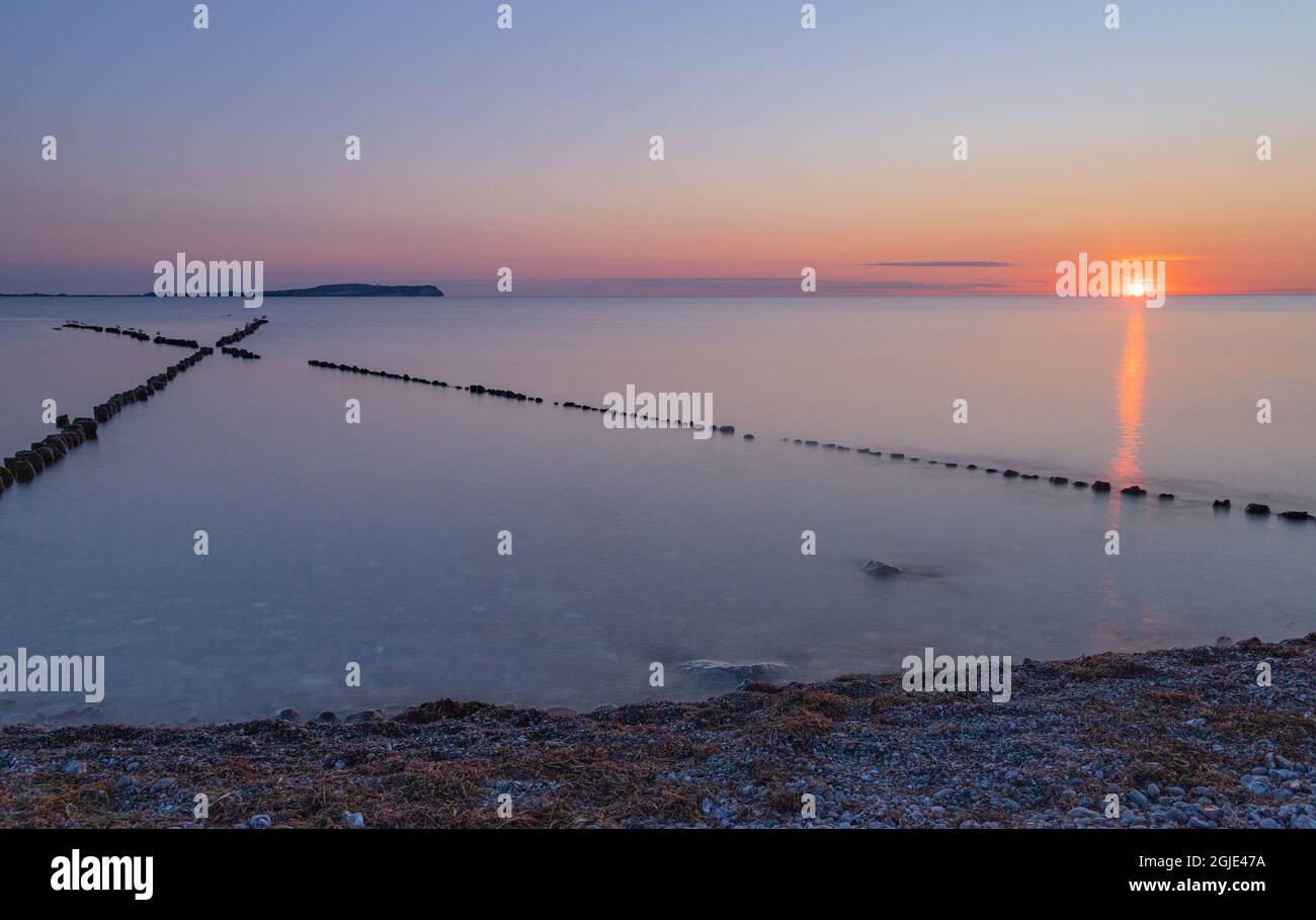 Küstenschutz mit Kreuzgroin (X-groin) mit der Insel Hiddensee im Hintergrund bei Sonnenuntergang Stockfoto
