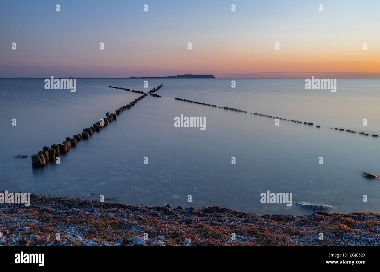 Küstenschutz mit Kreuzgroin (X-groin) mit der Insel Hiddensee im Hintergrund bei Sonnenuntergang Stockfoto