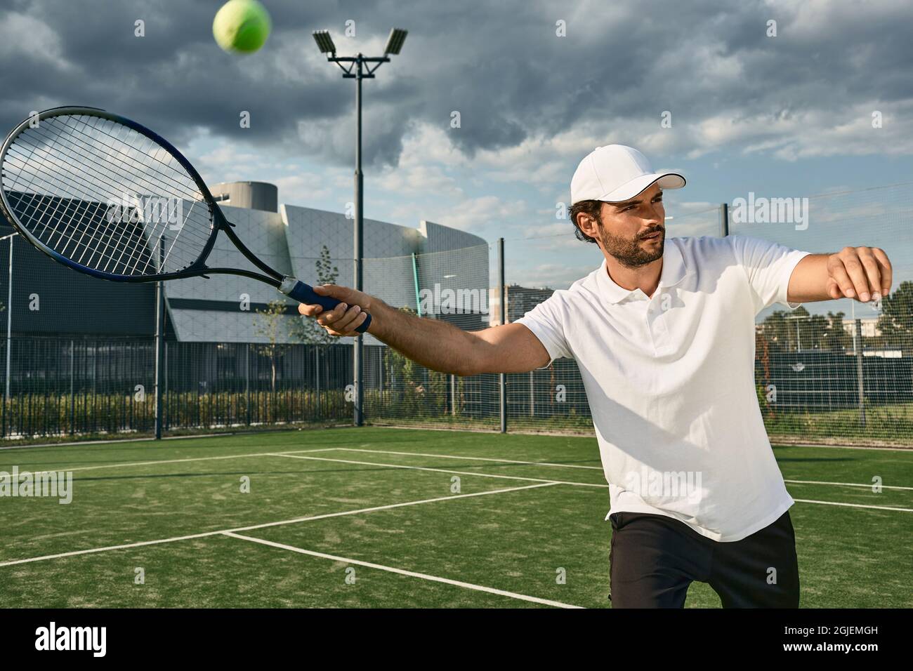 Tennisspieler, der im Freien beim Tennisspiel auf dem städtischen Rasenplatz spielt Stockfoto