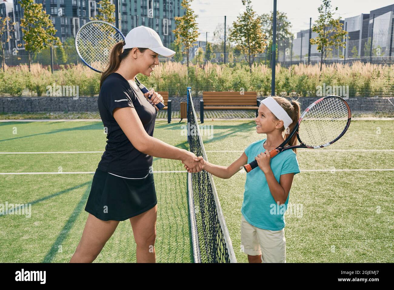 Lernen von Kindern Tennis. Eine Tennisspielerin, die vor dem Training Handshakes an die Rivalin in der Nähe des Tennisnetzes gab Stockfoto