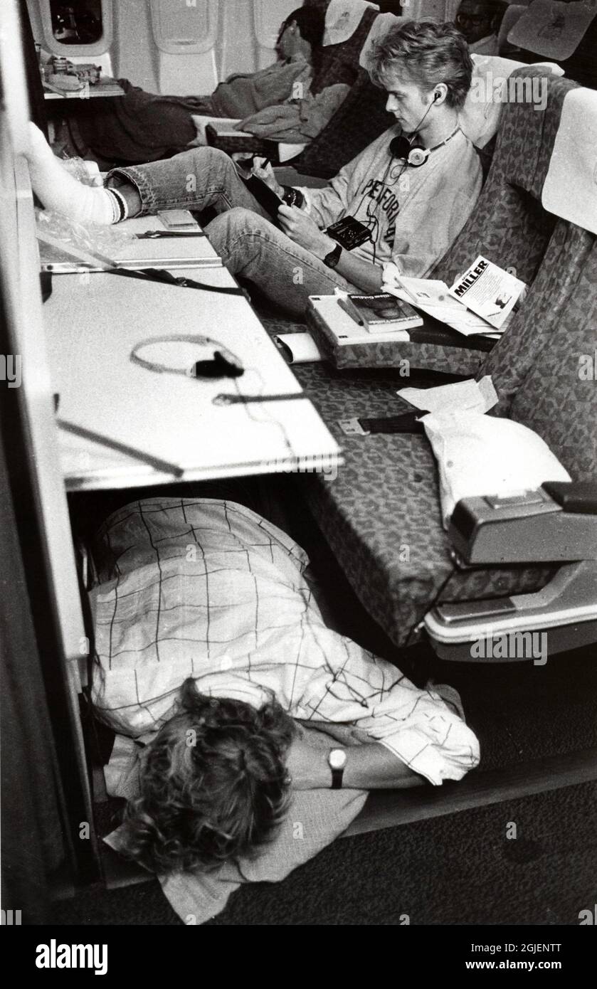 A-ha auf einem Flug von London nach Australien und einer Promotion-Tour. Manager Terry Slater schläft neben dem Fenster, Pal Waaktaar schreibt und Magne Furuholmen schläft auf dem Boden. Stockfoto