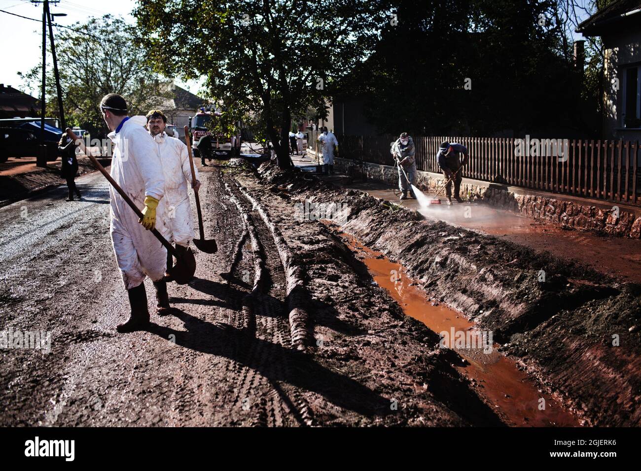 Man sieht, wie Menschen die Stadt Kolontar in Ungarn von dem giftigen roten Schlamm säubern. Ein Reservoir der nahegelegenen Ajka-Aluminiumoxid-Anlage gab etwa 800,000 Kubikmeter ätzenden roten Schlamm frei, der die Dörfer in der Umgebung überflutete. Stockfoto