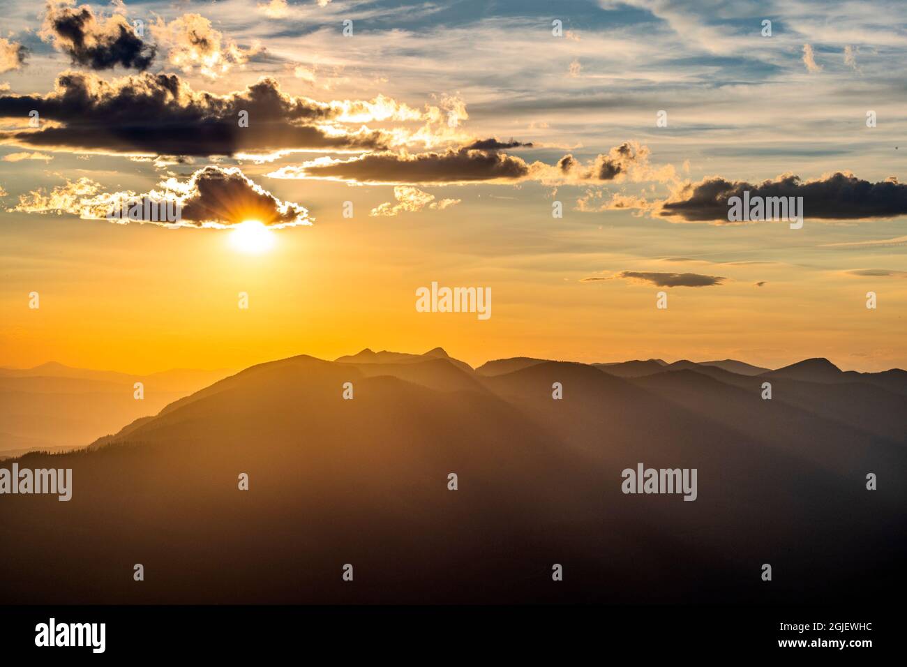 Die späte Sonne spättags späht hinter Cumulus-Wolken über der Whitefish Range in der Nähe von Whitefish, Montana, USA Stockfoto