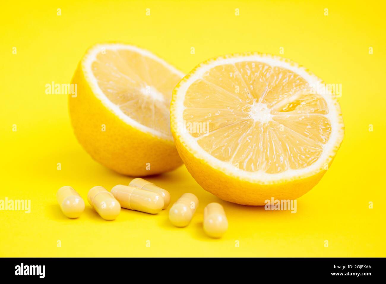 Vitaminkapseln. Vitamin-C-Pillen und gelbe Zitrone auf gelbem Hintergrund. Stockfoto