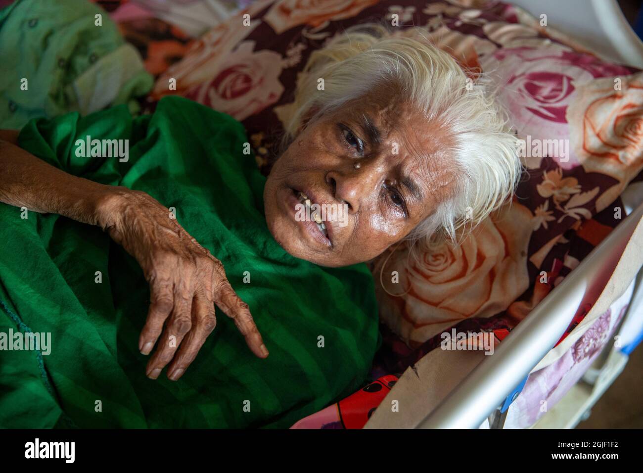 Eine ältere Bewohnerin, die sich in ihrem Bett im Alten Rehabilitationszentrum in Dhaka, Bangladesch, ausruhte. Stockfoto
