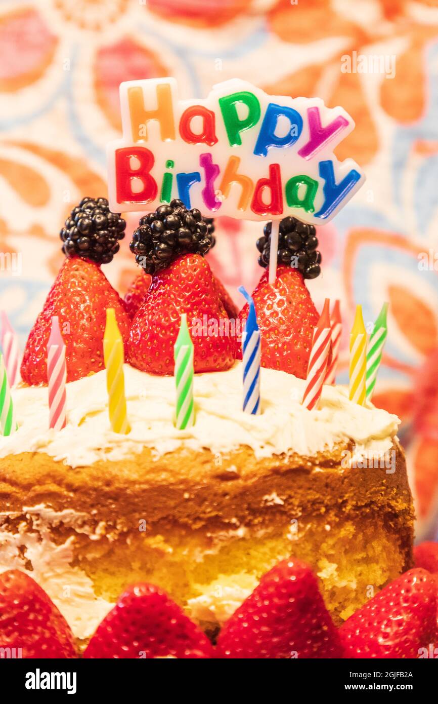 Geburtstag Kuchen mit Kerzen, Erdbeeren, Brombeeren und ein Schild mit der Aufschrift "Happy Birthday". Stockfoto