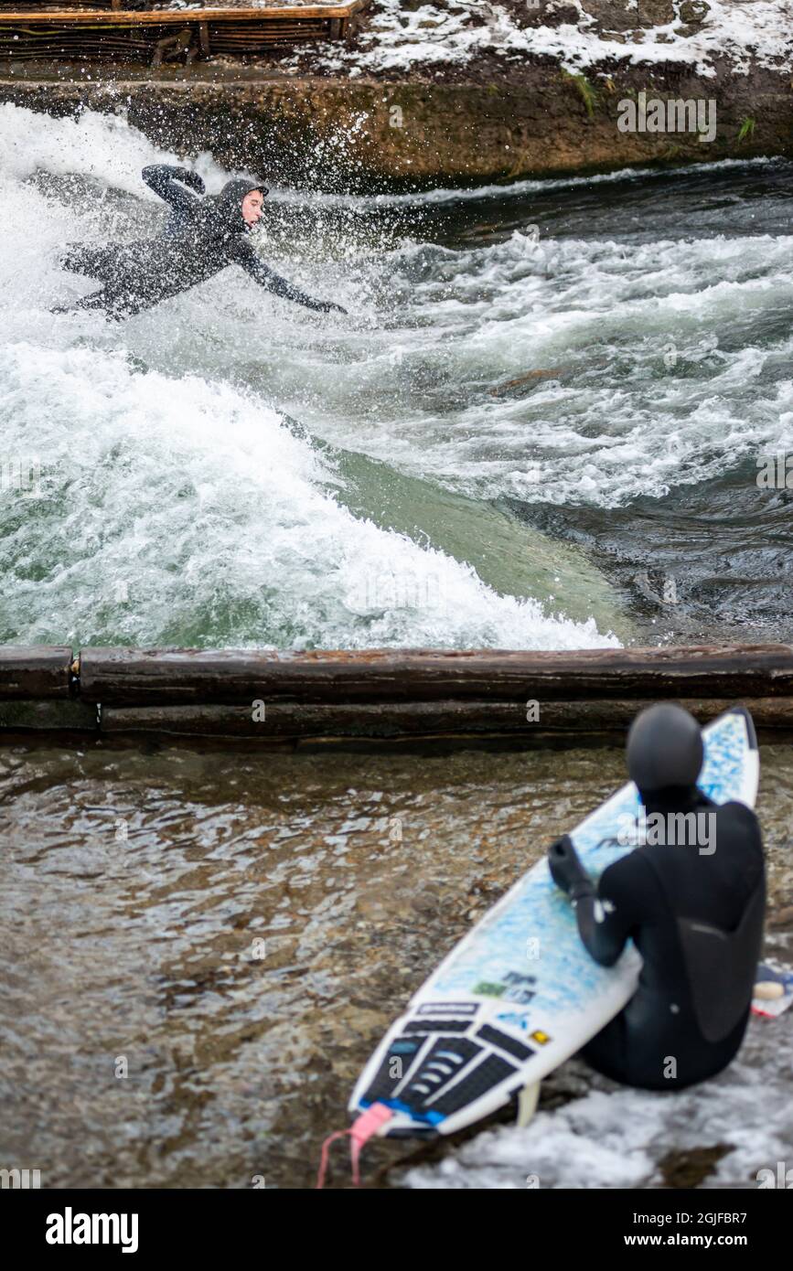 Surfer fahren stromaufwärts im Eisbach in München. Stockfoto