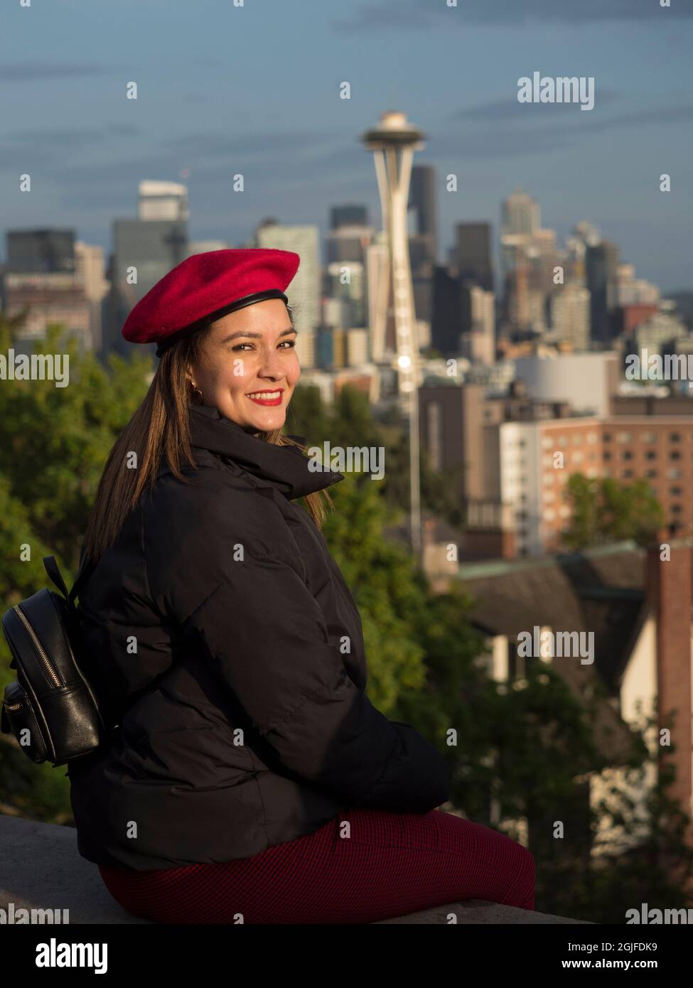 Usa, Staat Washington, Seattle. Eine junge Frau in einer roten Baskenmütze mit Blick über die Innenstadt von Seattle und Space Needle. (MR) Stockfoto