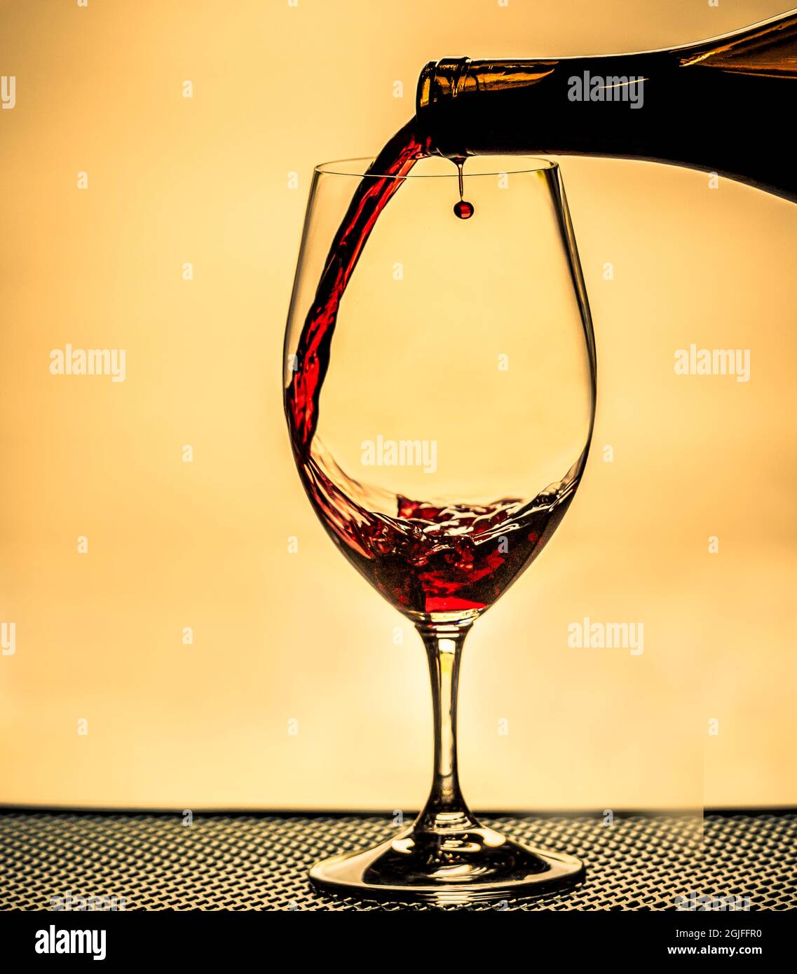 USA, Staat Washington, Spokane. Rotwein, der von der Mittagssonne im Glas beleuchtet wird, sorgt für einen perfekten runden Tropfen. Stockfoto