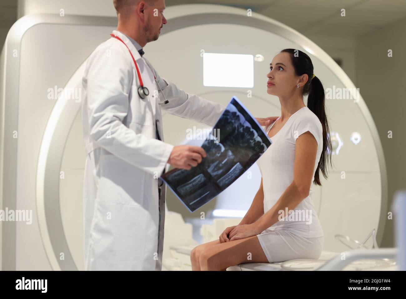 Männlicher Arzt erklärt weiblichen Patienten das Ergebnis der MRT-Untersuchung in der Klinik Stockfoto