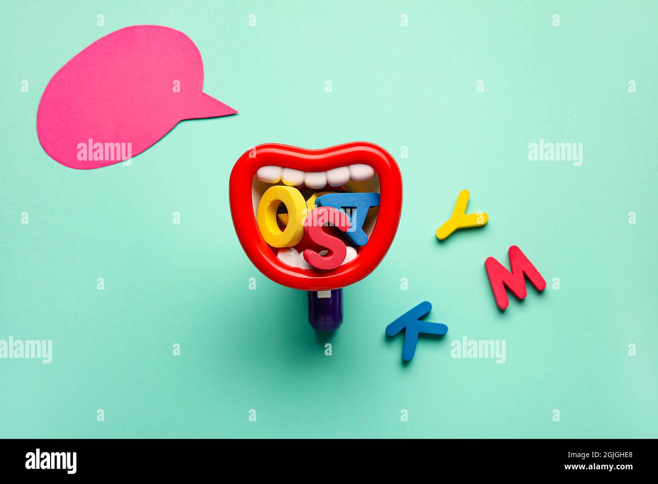 Spielzeug-Megaphon mit Buchstaben und Sprechblase auf farbigem Hintergrund Stockfoto