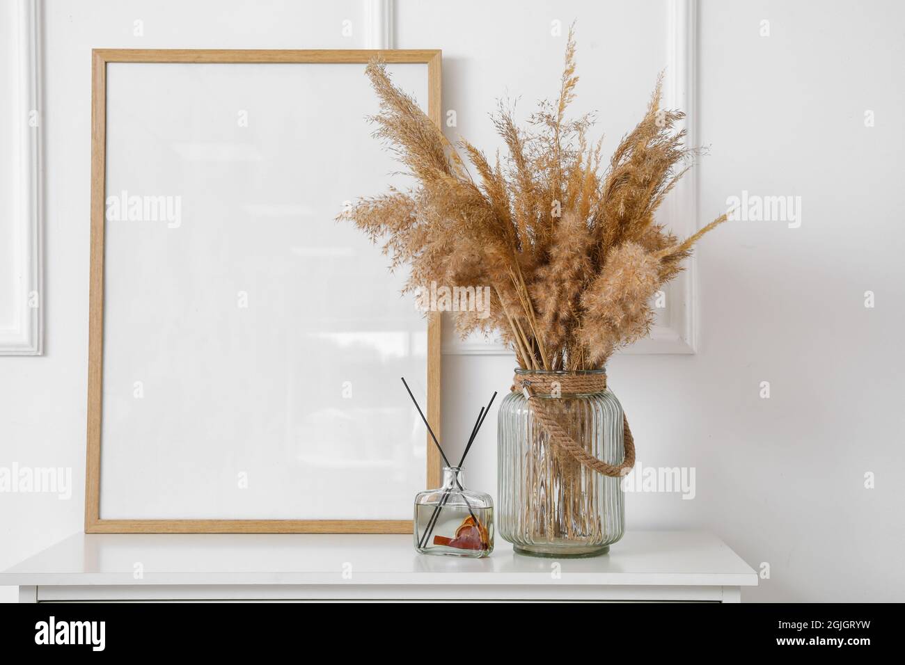 Vase mit trockenem Schilf und leerem Rahmen auf dem Tisch Stockfotografie -  Alamy