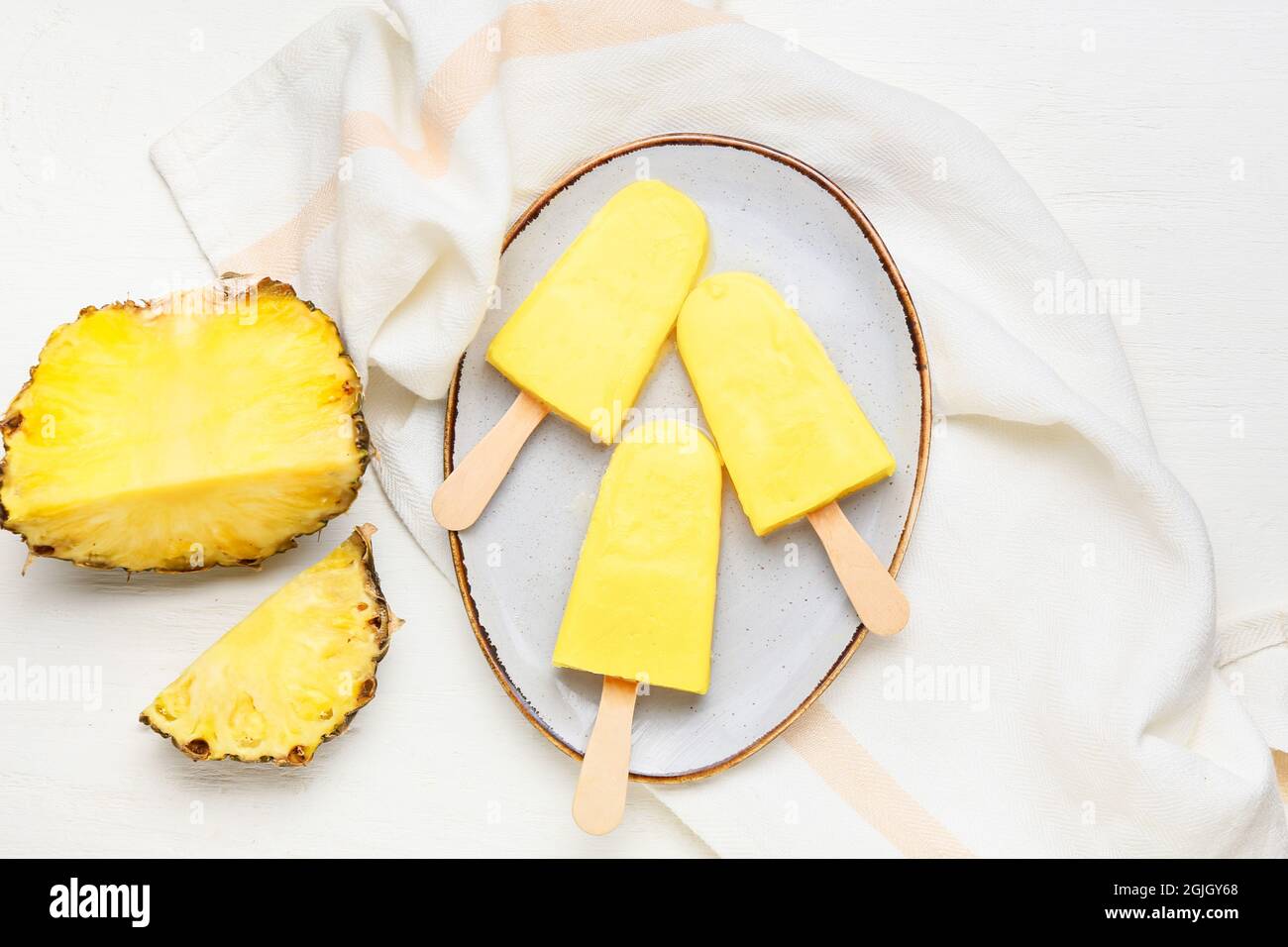 Teller mit leckeren Ananaspopsicles auf hellem Hintergrund Stockfoto