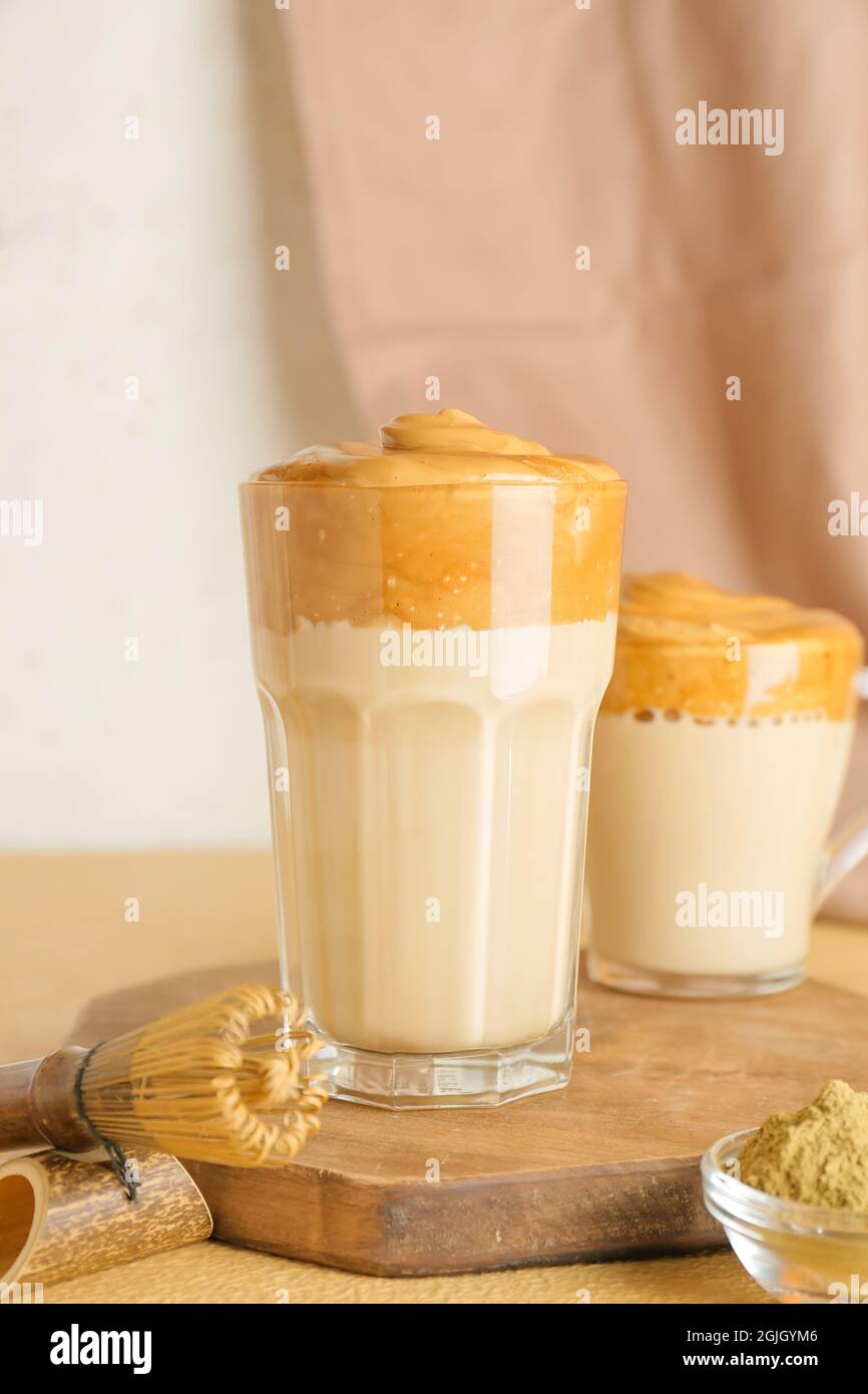 Glas und Tasse leckeren dalgona hojicha Latte auf dem Tisch Stockfoto